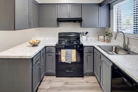 A modern kitchen with a black stove top oven and a marble counter top.
