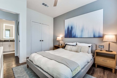 A bedroom with a large bed, a ceiling fan, and a painting on the wall.