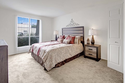 A bedroom with a bed, nightstand, and window.