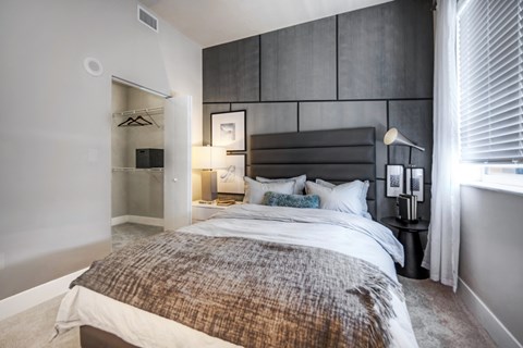 A bedroom with a large bed and a grey headboard.