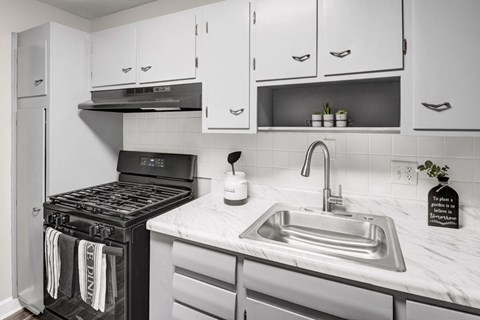 A modern kitchen with a black stove top oven and a marble counter top.