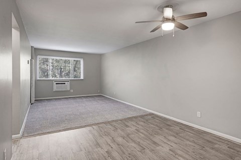 A room with a ceiling fan and a window with a view of trees.