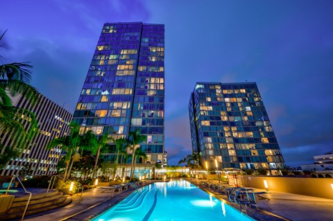 A swimming pool is in the foreground of a photo featuring two tall buildings.