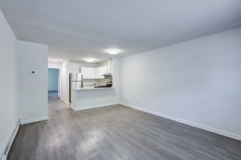 A spacious room with a kitchen in the background and a hardwood floor.