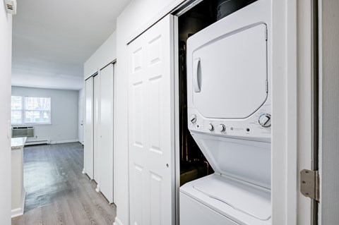 A white oven is installed in a kitchen with white walls and wooden flooring.