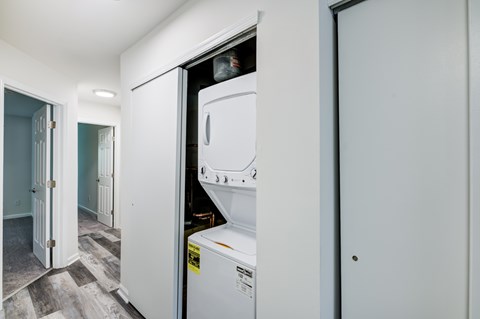 A white dishwasher is in a narrow space between a wall and a door.