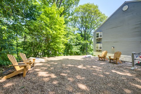 A backyard with a gravel area, two chairs, and a house.