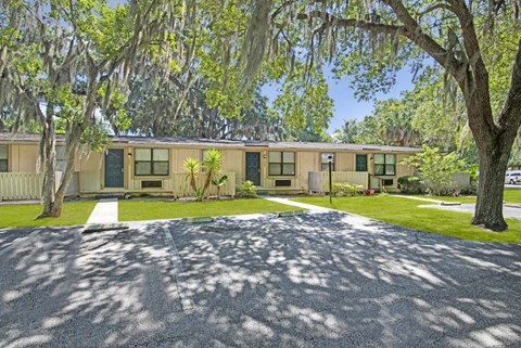 A building with a white picket fence and trees in front.