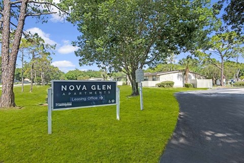 A sign for Nova Glen Apartments is in front of a grassy area.