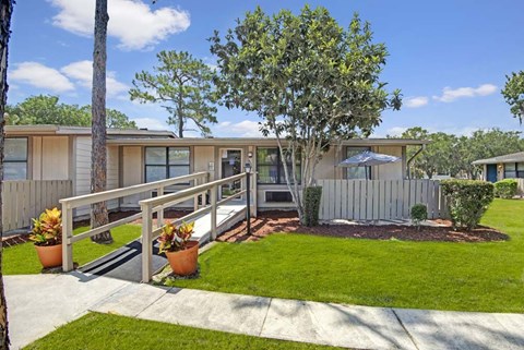 A house with a white picket fence and a tree in front.