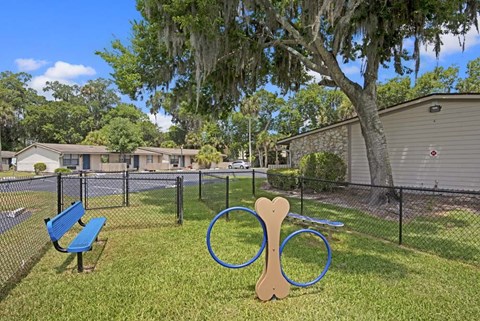 A playground with a blue bench and a wooden dog toy.