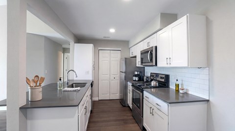 A modern kitchen with white cabinets and stainless steel appliances.