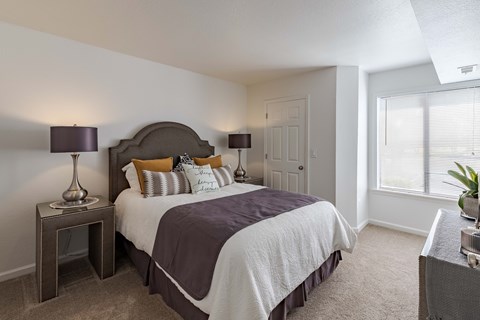 A bedroom with a large bed and a nightstand with a lamp.
