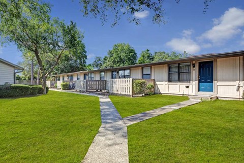 A long building with a blue door is surrounded by a green lawn.