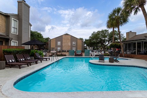 A swimming pool surrounded by lounge chairs and umbrellas.