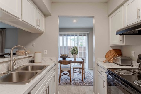 A kitchen with white cabinets and a stainless steel sink.