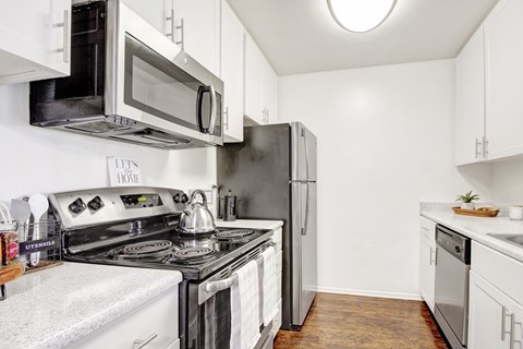 A kitchen with a black stove top oven and a silver microwave above it.