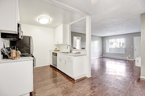 A kitchen with white cabinets and a wooden floor.