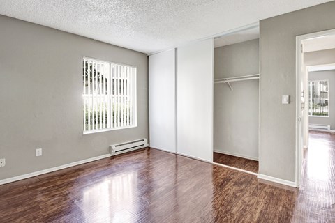 A room with wooden floors and a window with blinds.