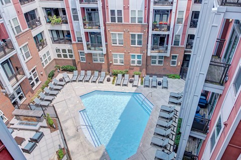 A swimming pool surrounded by lounge chairs and buildings.