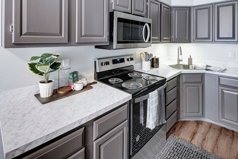 A kitchen with a white counter top and a black stove top oven.
