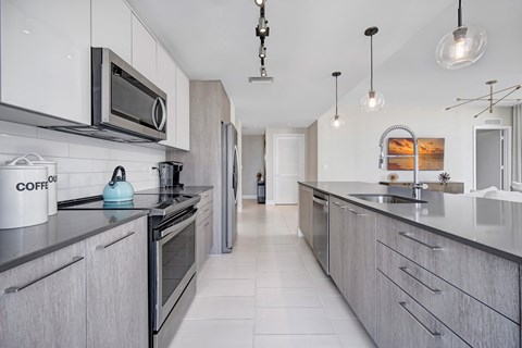A modern kitchen with a stainless steel sink and a dining area with a table set for two.