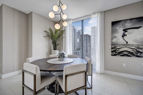 A modern living room with a large white sofa and a kitchen area with a bar.