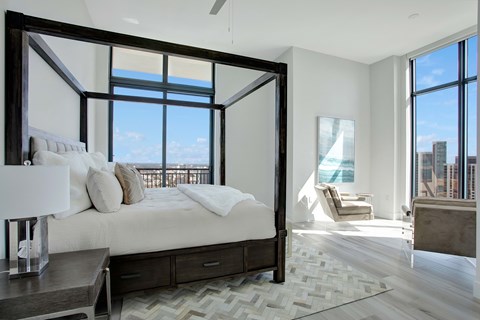 A large bedroom with a large bed and a view of the city.