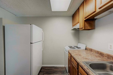 A kitchen with a white refrigerator, brown cabinets, and a marble countertop.