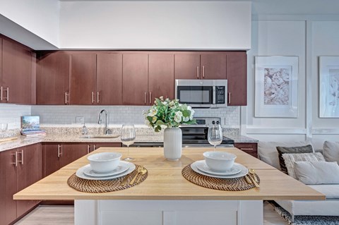 A modern kitchen with a wooden table set for two.