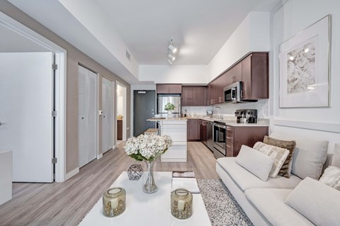 A modern kitchen with a white couch and a coffee table with vases on it.