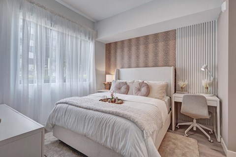 A bedroom with a large bed and a desk with a chair.
