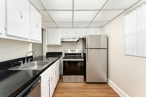 A kitchen with a stainless steel refrigerator, oven, and sink.