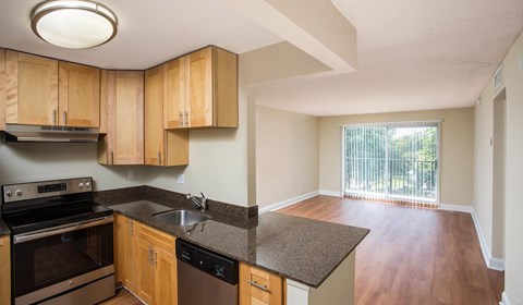 A kitchen with wooden cabinets and a black dishwasher.