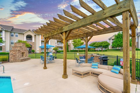 A wooden pergola over a patio with a couch and chairs.