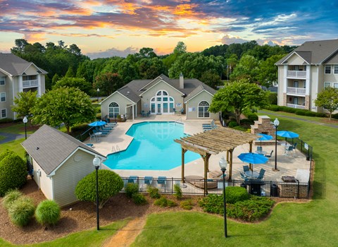 A beautiful sunset view of a pool area with a pavilion and loungers.