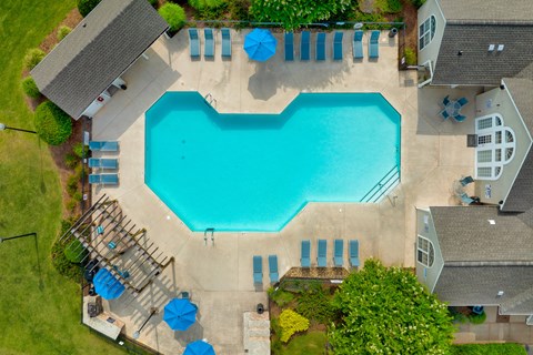 A large swimming pool surrounded by a few buildings and trees.