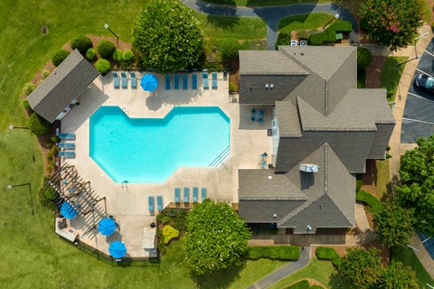 A large swimming pool surrounded by a small building and trees.