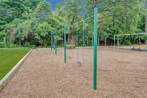 A playground with a swing set and a green pole.