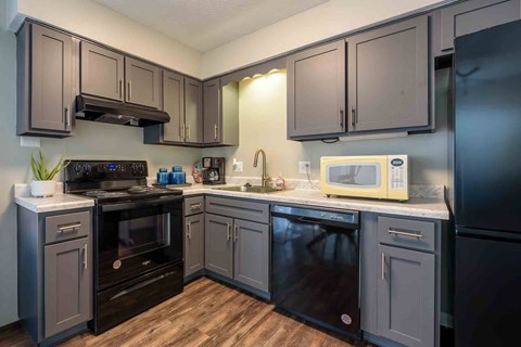 A kitchen with black appliances and wooden floors.