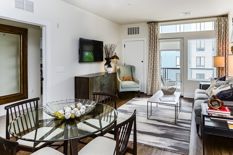 A modern living room with a glass dining table and chairs.