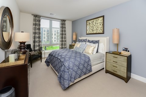 A bedroom with a large bed and a window with curtains.