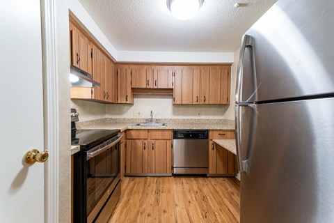 A kitchen with wooden cabinets and a stainless steel refrigerator.