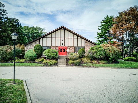 A building with a red door is surrounded by greenery.