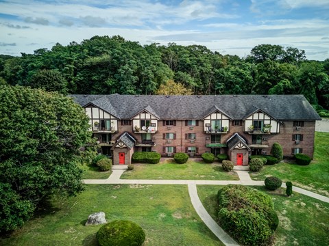A large building with a red door is surrounded by greenery.
