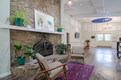 A living room with a stone fireplace and a wooden chair.