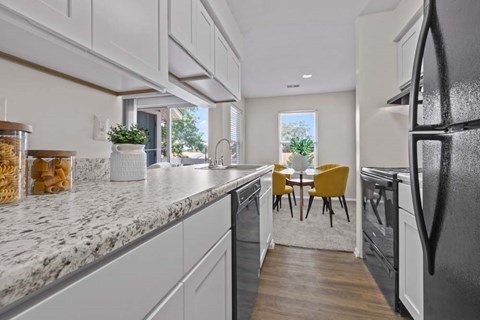 A kitchen with a marble countertop and a refrigerator on the right.