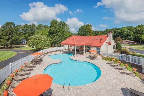 A large outdoor swimming pool surrounded by orange sun loungers.