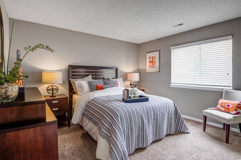 A bedroom with a bed, nightstand, and chair.