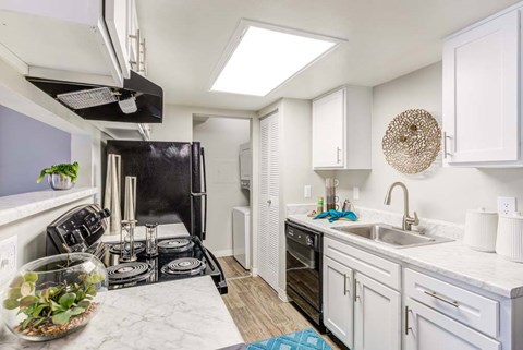 A kitchen with a black stove top oven and white cabinets.
